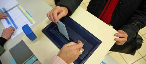 Una mujer introduce su voto en una urna. Una mujer introduce su voto en una urna.