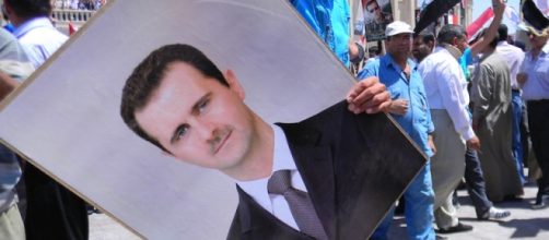 Un manifestante con la foto di Assad