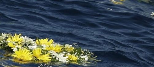 Corona di fiori per i migranti morti in mare.