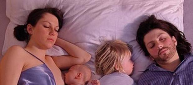 Una pareja con sus hijos en la cama Una pareja con sus hijos en la cama