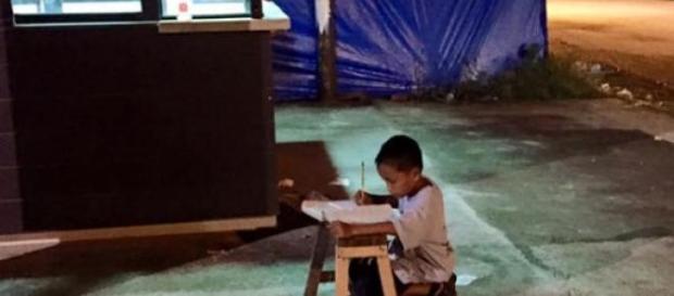 Menino aproveita a luz da rua para estudar Menino aproveita a luz da rua para estudar