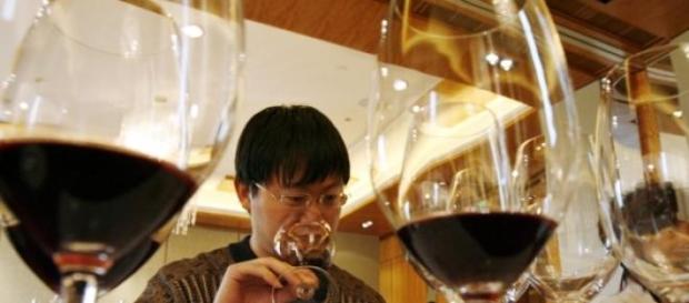 Cinese degusta un bicchiere di vino rosso Cinese degusta un bicchiere di vino rosso