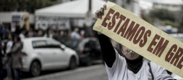Manifestante exibindo faixa estamos em greve Manifestante exibindo faixa estamos em greve