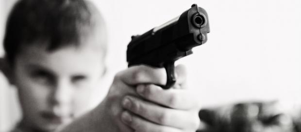 Copil cu o armă de foc în mână Copil cu o armă de foc în mână