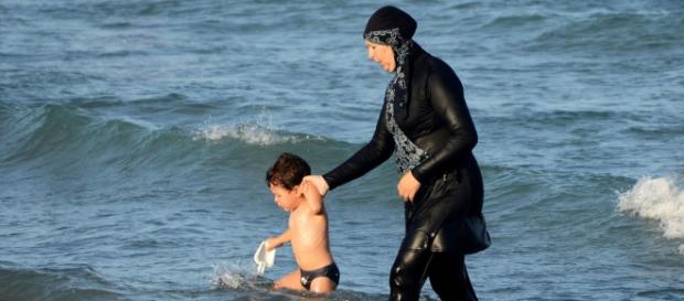 Mujer con burkini acompaña a su hijo a orillas del mar Mujer con burkini acompaña a su hijo a orillas del mar