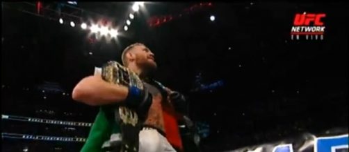 Conor McGregor celebrando su victoria con ambos cinturones.