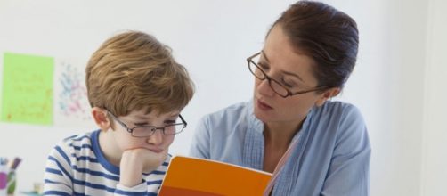 Un bambino legge un testo da un quaderno
