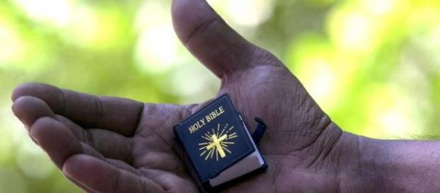 Una Bibbia in miniatura nella mano di un uomo Una Bibbia in miniatura nella mano di un uomo