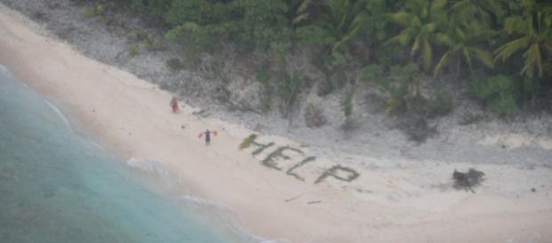 Bărbații salvați de pe insula pustie făcând semne avionului cu vestele de salvare lângă cuvântul HELP - Foto: US NAVY Bărbații salvați de pe insula pustie făcând semne avionului cu vestele de salvare lângă cuvântul HELP - Foto: US NAVY
