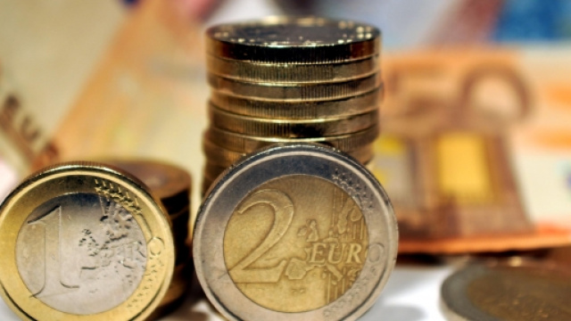 Due monete davanti una pila di monete e tante banconote