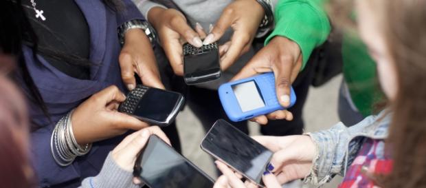 Un gruppo di ragazzi intenti a leggere i propri cellulari Un gruppo di ragazzi intenti a leggere i propri cellulari