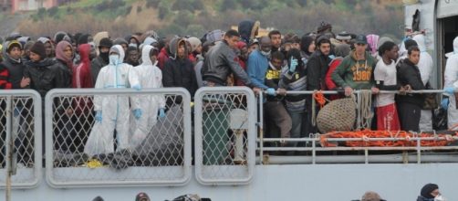 Operazioni di sbarco per un folto gruppo di migranti in un porto italiano