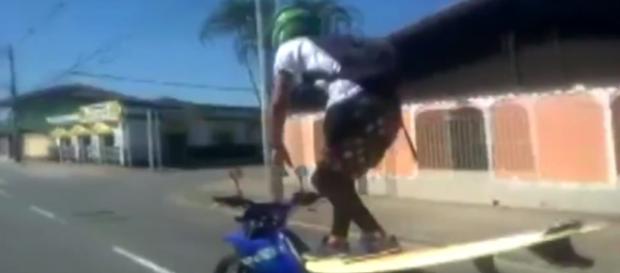 Motociclista surfa enquanto pilota sua moto. Motociclista surfa enquanto pilota sua moto.