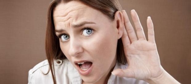 Une femme tendant l'oreille afin de mieux percevoir les sons Une femme tendant l'oreille afin de mieux percevoir les sons