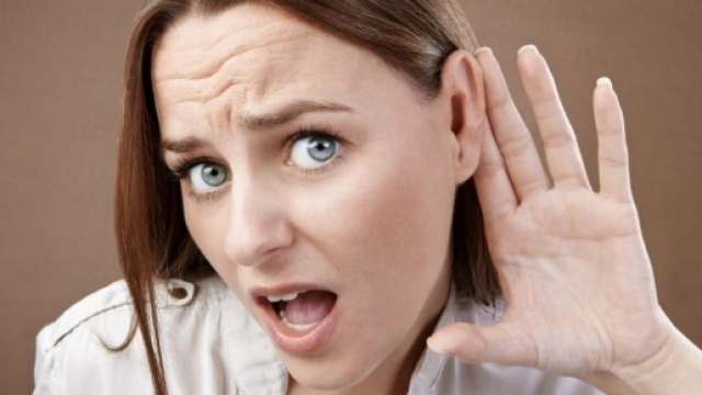 Une femme tendant l'oreille afin de mieux percevoir les sons