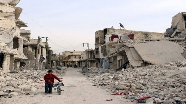 Un bambino attraversa una strada colma di macerie ad Aleppo.