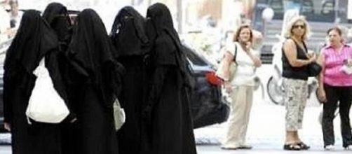 Un gruppo di donne in niqab separato da un gruppo di donne occidentali