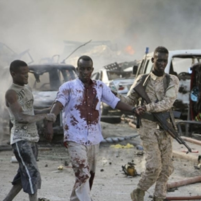 A Somali soldier and local both help a civilian who was wounded in the blast in the capital.