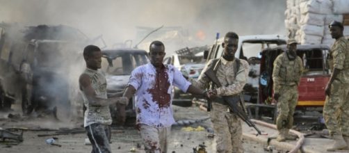 A Somali soldier and local both help a civilian who was wounded in the blast in the capital.