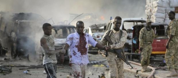 A Somali soldier and local both help a civilian who was wounded in the blast in the capital. A Somali soldier and local both help a civilian who was wounded in the blast in the capital.