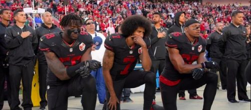 San Francisco 49ers' Eli Harold, Colin Kaepernick and Eric Reid kneel during the national anthem. [Image via Marie Louise Meewah/Flickr]