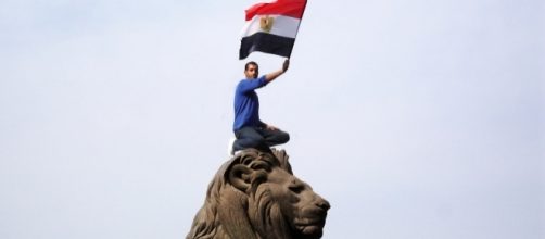 An Egyptian protestor waves the Egyptian flag. Photo by Kodak Agfa via Wikipedia Commons.