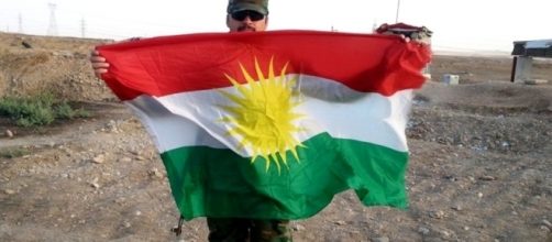 Peshmerga fighter holding flag. [Image Credit: Kurdishstruggle/Flickr]