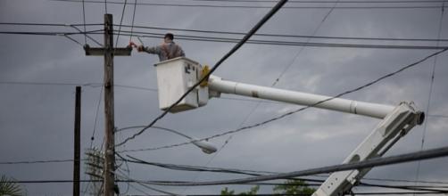 Electric company repairing a power pole in Puerto Rico (Image credit – Andrea Booher – Wikimedia Commons)