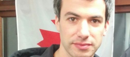 Nathan Fielder standing beyond a Canadian flag [Image: Northwest via Wikimedia Commons]