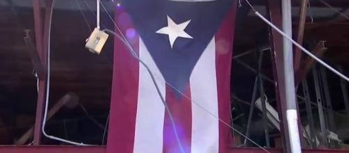 Puerto Rican flag surrounded by rubble / [Image credit: NBC News/YouTube]
