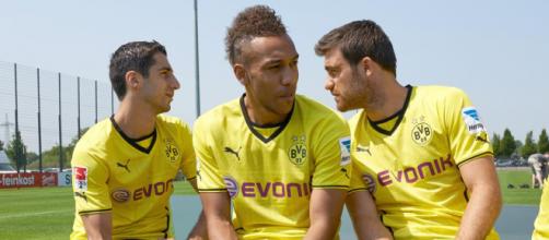 Borussia Dortmund striker, Pierre-Emerick Aubameyang (Center) sandwiched by his teammate on a bench. (Image via TotalFootball/Flickr)