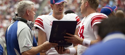 Eli Manning discussing the playbook [image credit: AJ Guel/ Wikimedia Commons]