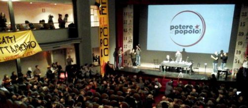 Un momento dell'assemblea di Potere al Popolo: sullo sfondo il simbolo