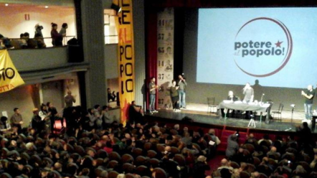 Un momento dell'assemblea di Potere al Popolo: sullo sfondo il simbolo