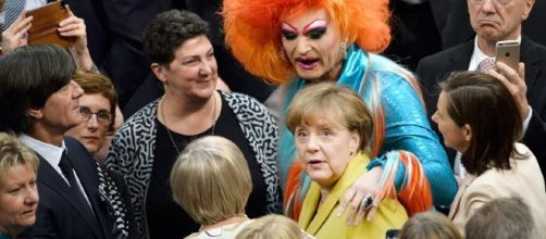 Olivia Jones abbraccia la Merkel subito dopo l'elezione del nuovo Presidente davanti allo sguardo divertito di Loew