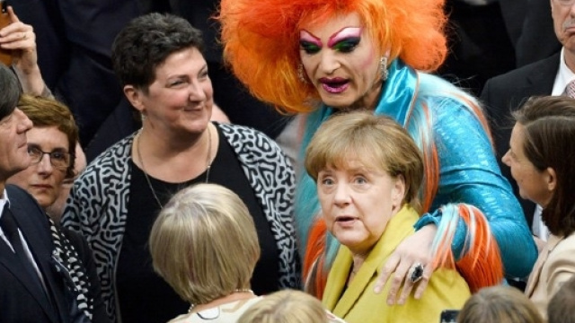 Olivia Jones abbraccia la Merkel subito dopo l'elezione del nuovo Presidente davanti allo sguardo divertito di Loew