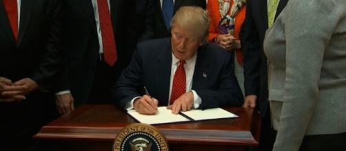 Donald Trump is signing the order. Photo via CNN.com.