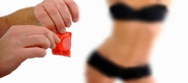 Homem abrindo preservativo e mulher de fundo Homem abrindo preservativo e mulher de fundo