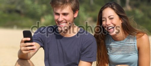 Gracioso hombre y mujer riendo mirando el teléfono inteligente ... - depositphotos.com