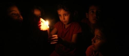 Niños palestinos se alumbran con una vela (cortesía ONU).