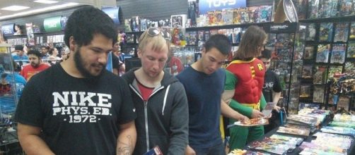 Customers pick up copies of free comics made available at a comic shop. [Image via Blasting News image library/levelupentertainment.com]