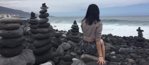 Chica italiana alrededor de apachetas en la playa del Castillo San Felipe, Puerto de la Cruz