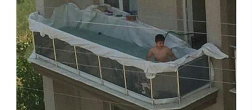 Menino brinca na piscina improvisada na sacada de um apartamento (Foto: Reprodução)