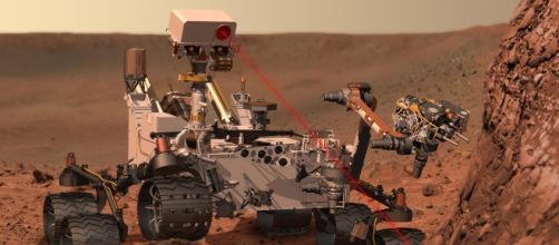 Un rendeering di Curiosity mentre punta il suo spettrometro laser sul suolo marziano