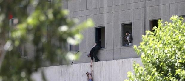 Homem entrega criança a guarda por uma janela do Parlamento iraniano após ataque Homem entrega criança a guarda por uma janela do Parlamento iraniano após ataque