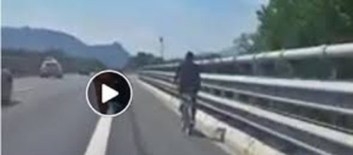 Migrante in bicicletta in autostrada