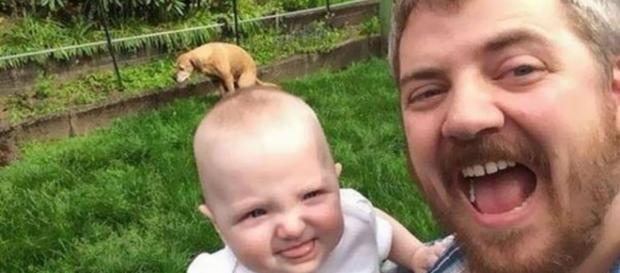Il piccolo sorride con il papà mentre il cagnolino è impegnato in altre faccende Il piccolo sorride con il papà mentre il cagnolino è impegnato in altre faccende