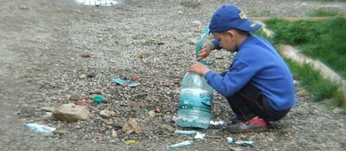 Niño pobre con sus juguetes: una botella vieja de agua y piedras.
