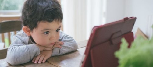 Bambino guarda cartone animato su un tablet.