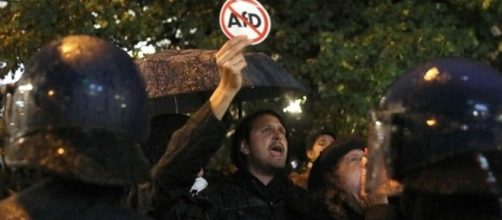 Manifestante antifascista davanti al cordone di polizia con un cartello anti-AfD